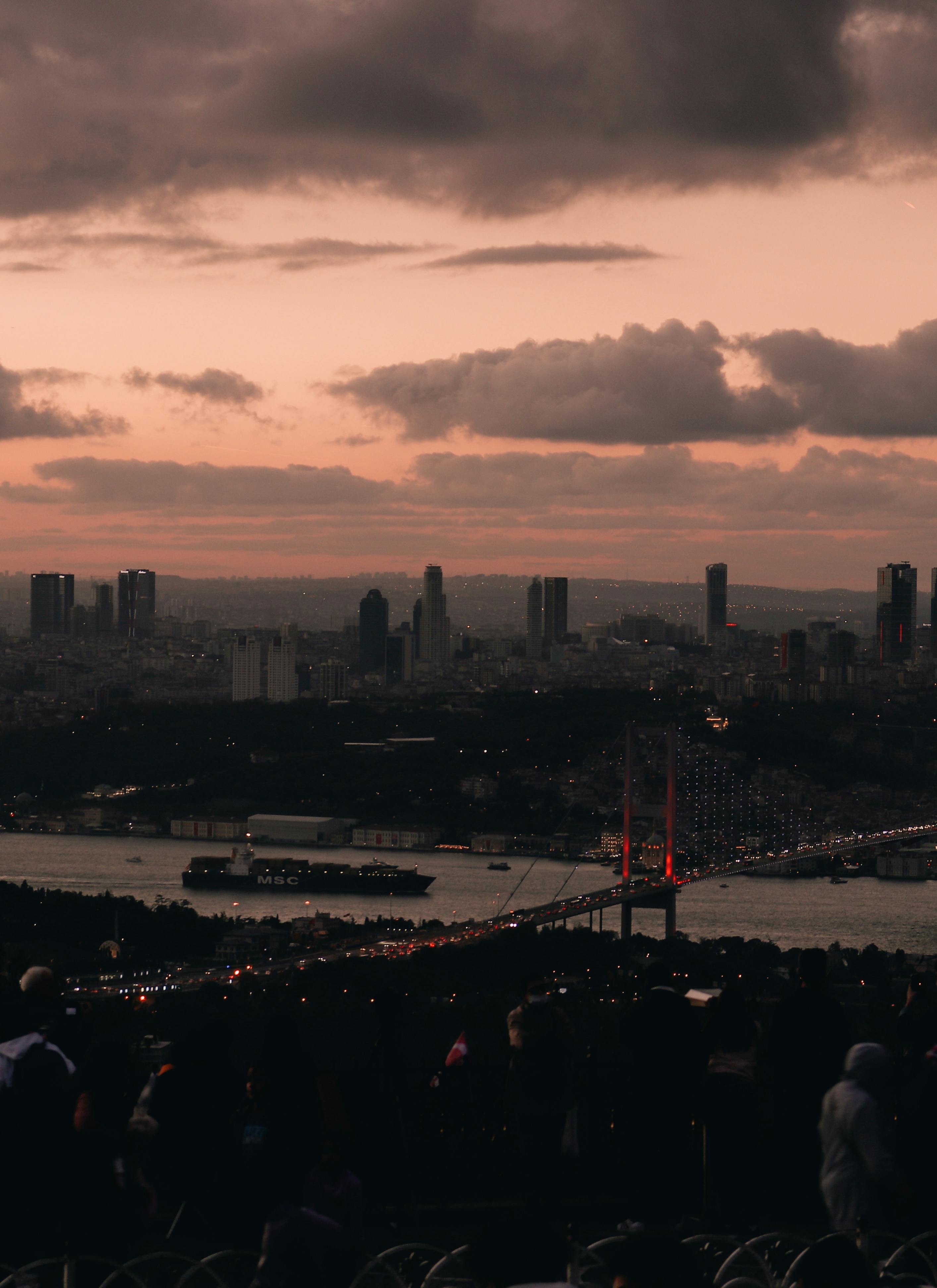 Aerial view of Istanbul's skyline and Bosphorus Bridge at sunset, showcasing a dramatic urban landscape.