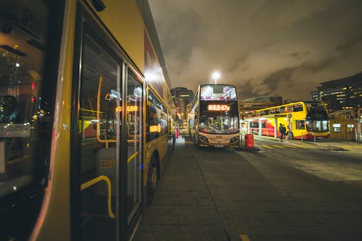 City buses at a bustling nighttime bus stop in Kowloon, showcasing urban public transportation.