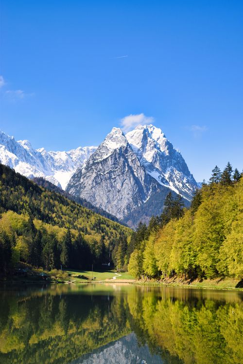 Free Snow-capped mountains towering over a peaceful lake with water reflection. Stock Photo