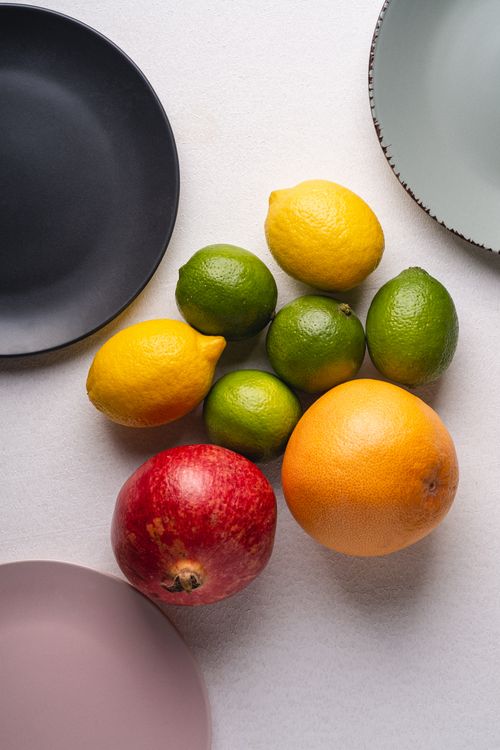Free A vibrant assortment of citrus fruits and a pomegranate arranged on various plates. Stock Photo