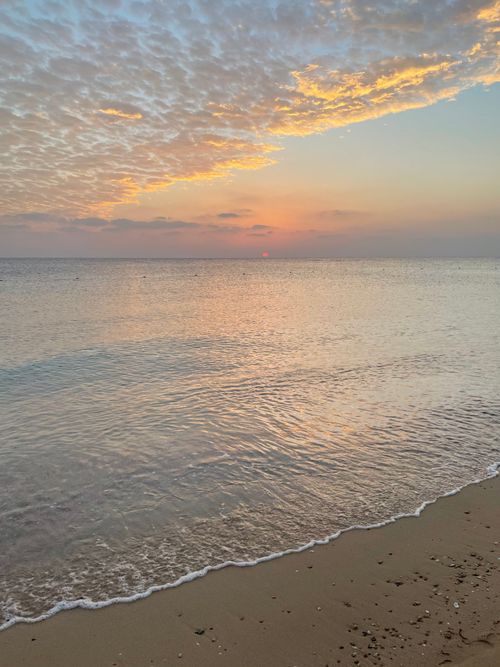Free A tranquil beach scene at sunrise with gentle waves and colorful sky, perfect for relaxation themes. Stock Photo
