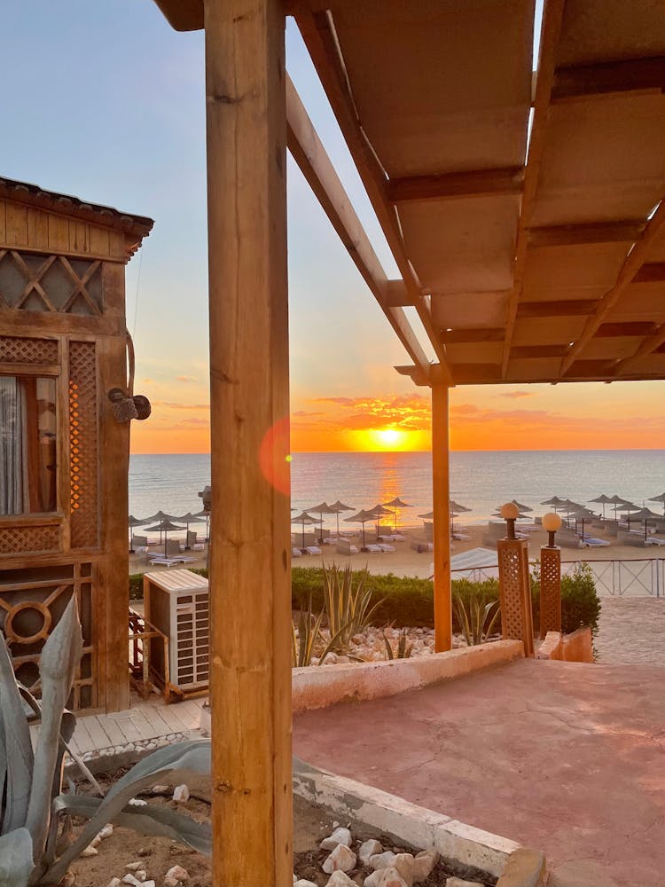 Brown Wooden House Near Body Of Water During Sunset