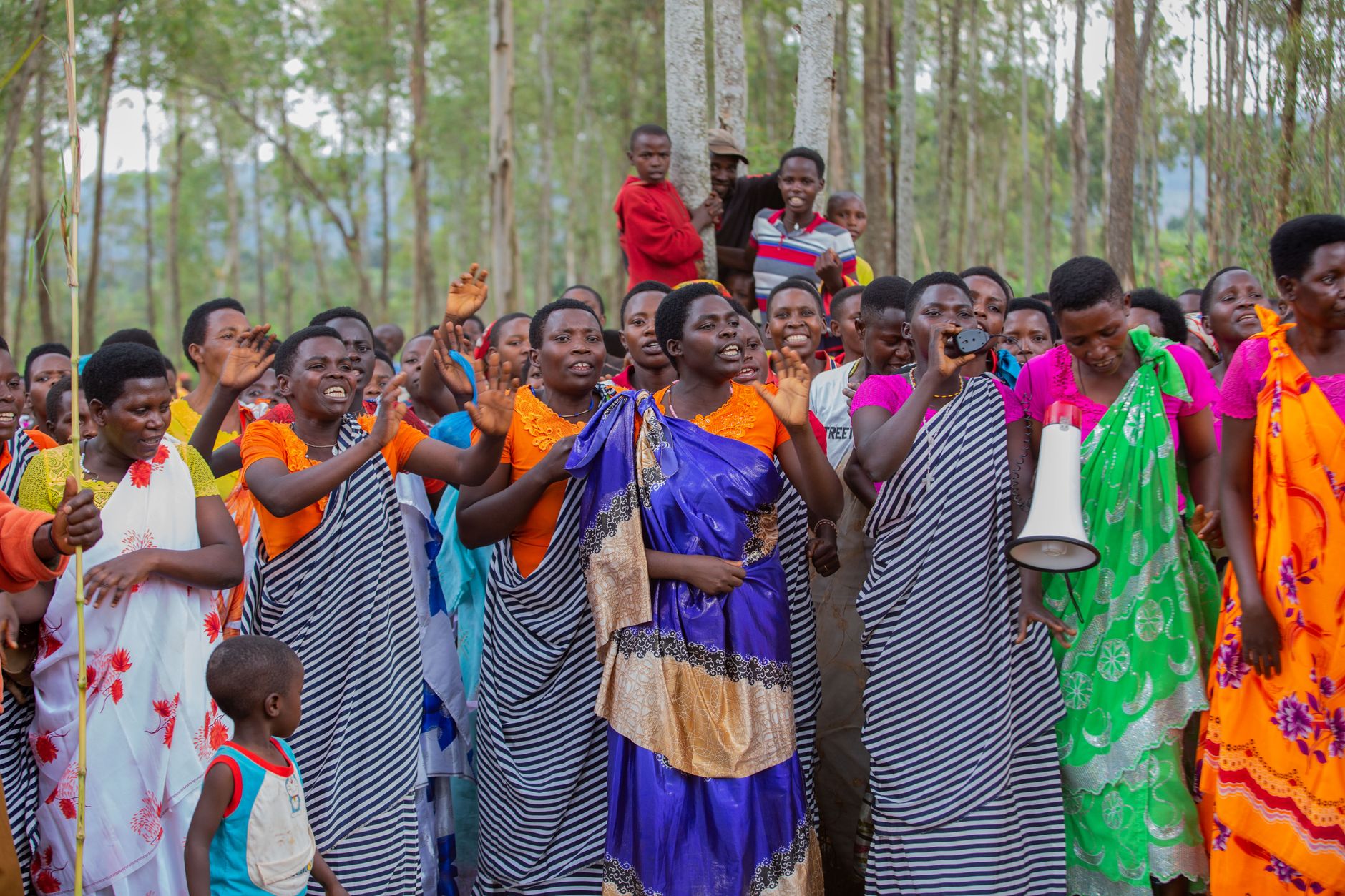 A joyous group of people in traditional attire celebrating in a forest setting.