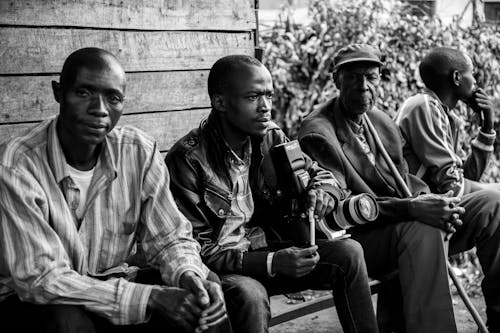 Grayscale Photo of Men Sitting on the Bench