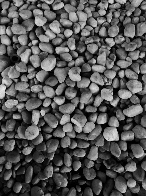 Close-up black and white image of a pile of small pebbles forming a textured surface.