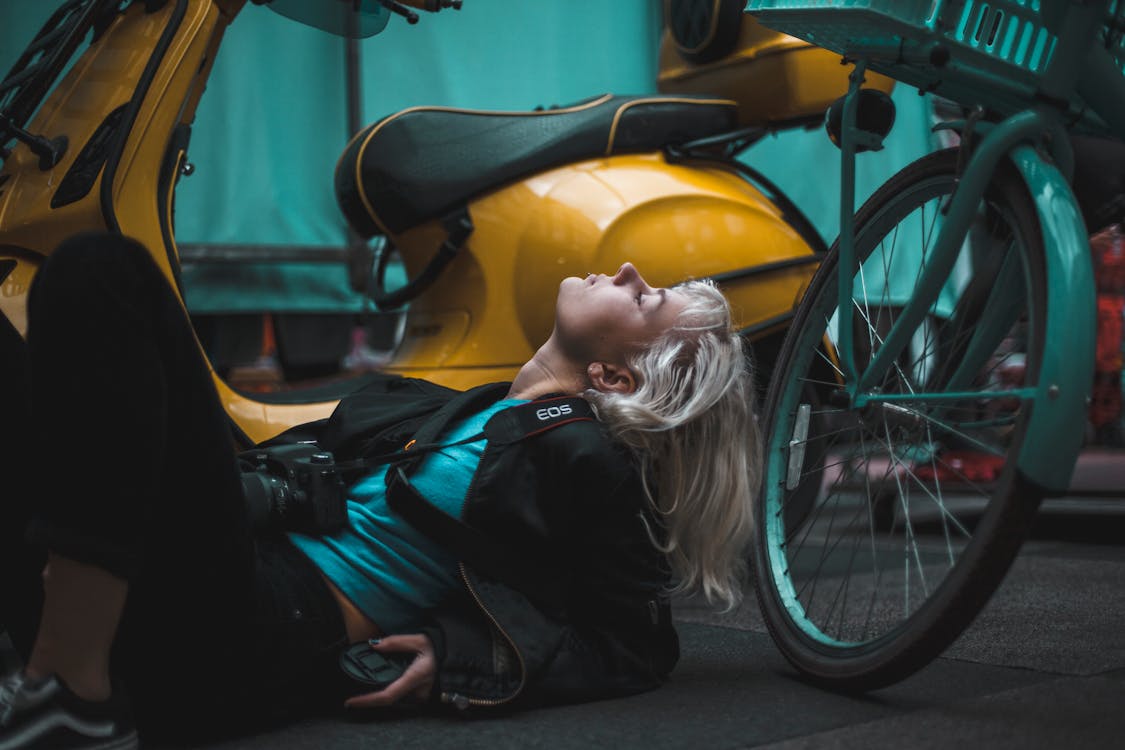 Photography of Woman Laying on Ground Near Scooter
