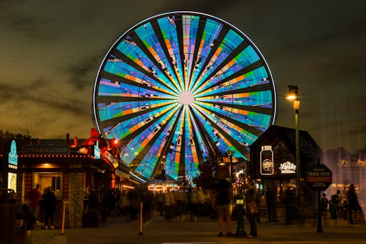 Colorful ferris wheel illuminated at night in Pigeon Forge, TN, showcasing a lively amusement park atmosphere.