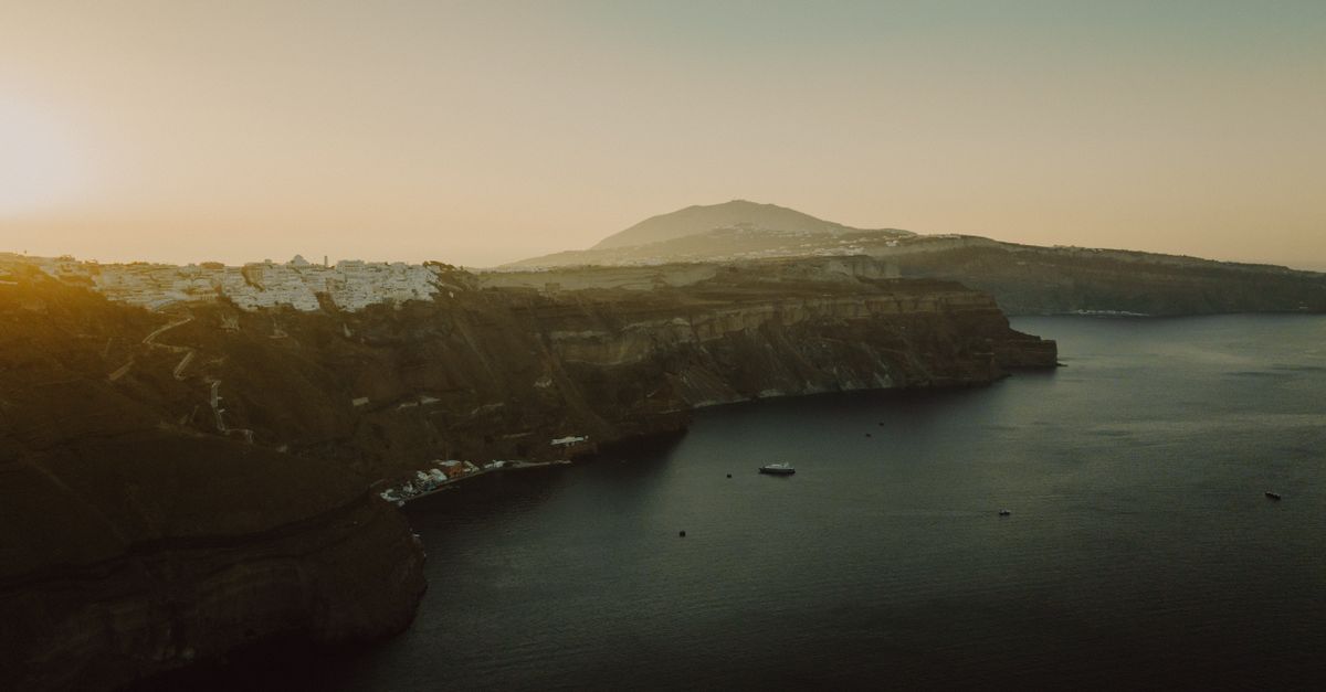 Capture of Thera's dramatic cliffs in Santorini, Greece, at sunset. A tranquil sea view.