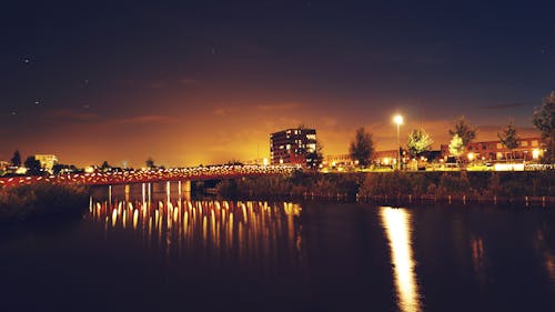 Bridge over Water Across Building during Nighttime