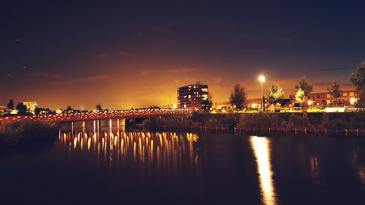 Bridge over Water Across Building during Nighttime