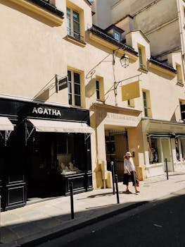 一名妇女漫步在法国巴黎皇家村阳光明媚的标志性街道上