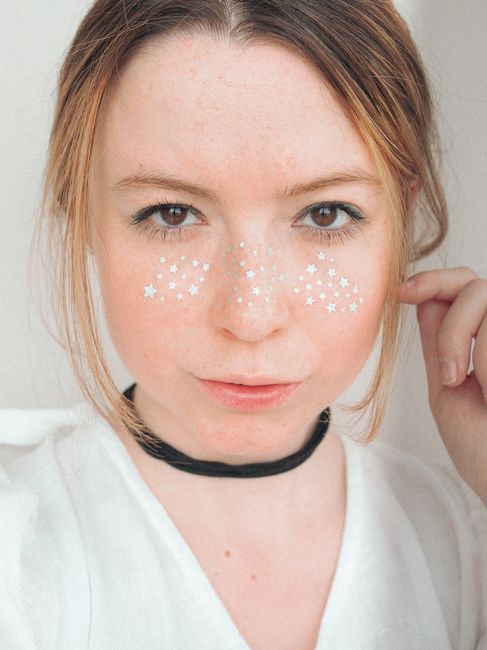 A captivating woman with star accents on her face in a bright setting.
