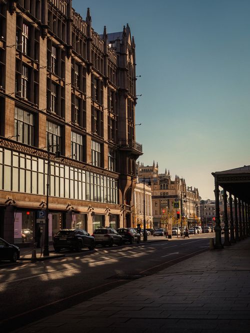 Free A serene city street lined with historic buildings under a clear blue sky. Stock Photo