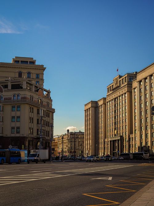 Free Street view of city buildings under clear blue sky, showcasing urban architectural style. Stock Photo