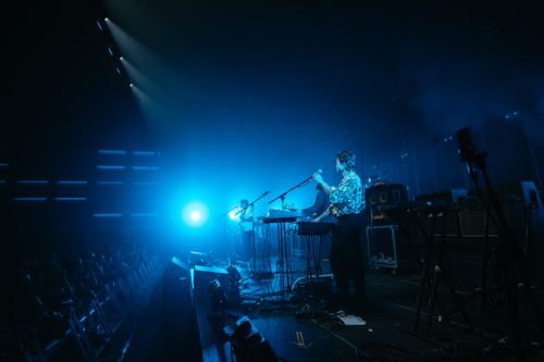 Free Energetic live band performance on stage with vibrant blue lighting and audience engagement. Stock Photo