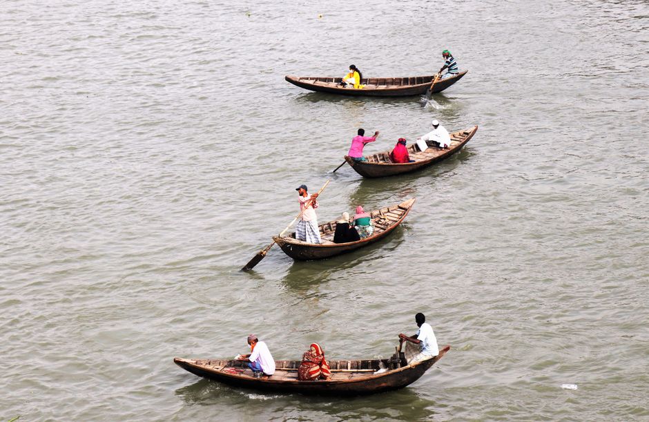 Aerial view of traditional wooden boats with passengers navigating waters in Dhaka, Bangladesh.