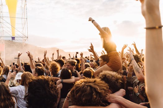 Energetic crowd enjoying live music at a festival during sunset.