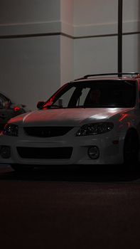 A parked white car captured at night with dramatic lighting.