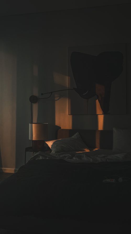 Free A serene bedroom with warm lighting highlighting the bed and decor, creating a cozy atmosphere. Stock Photo