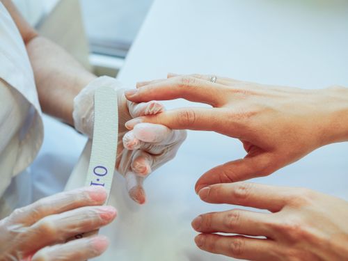Free Close-up of a manicurist shaping nails using a file in a salon. Stock Photo