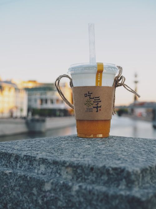 Free Iced beverage in cup with straw on riverfront ledge under clear sky. Stock Photo