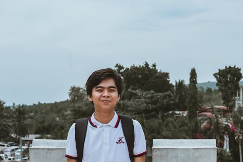 Man Wearing White Polo Shirt and Black Backpack