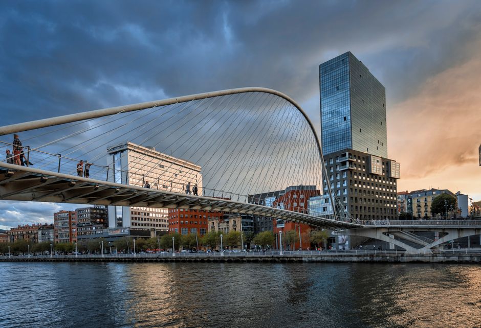 Una vista impresionante de un moderno puente colgante y el horizonte de la ciudad al atardecer.