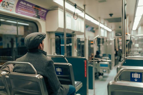 Man in Gray Hoodie Sitting on Train Seat