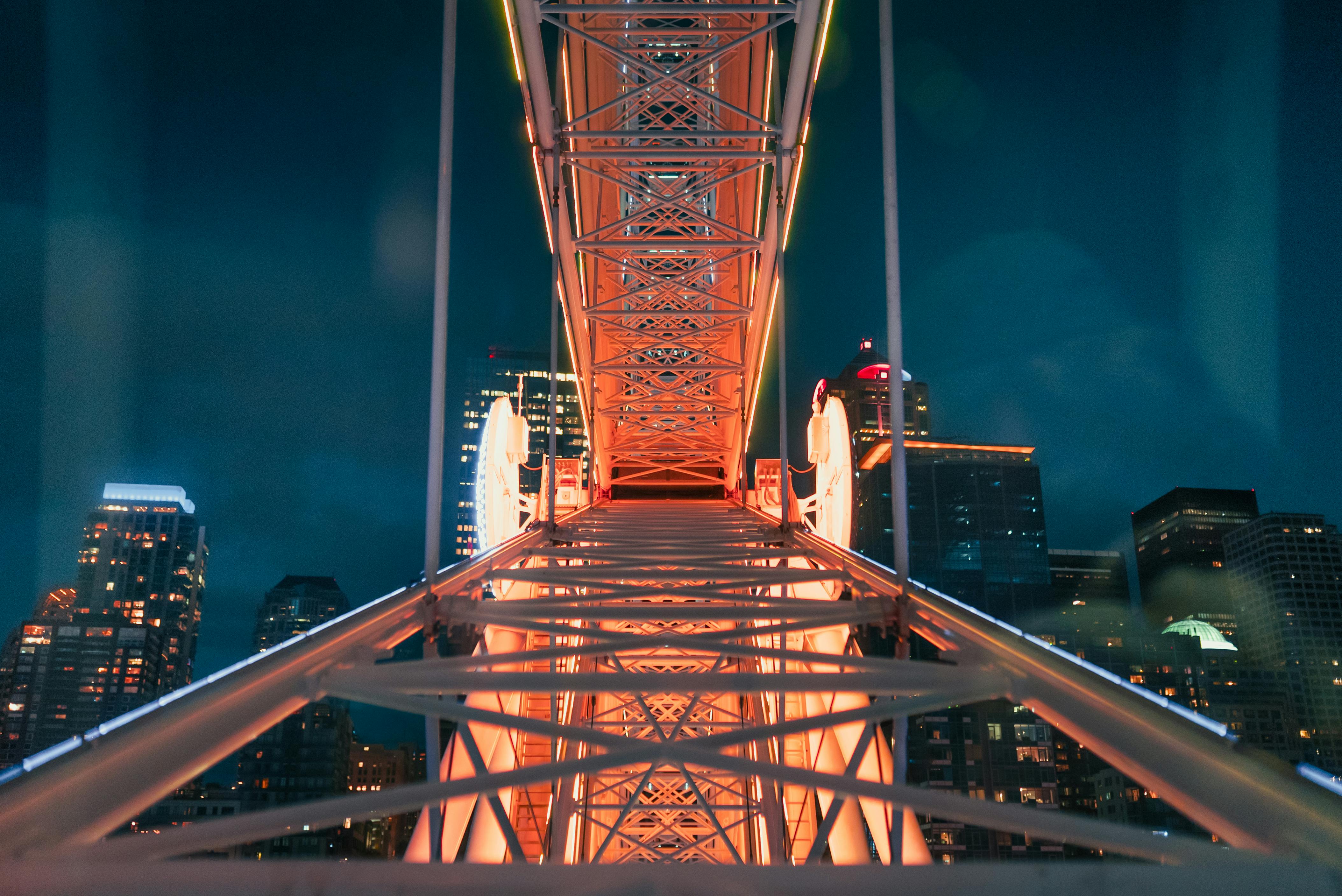 man in black shirt and blue denim jeans walking on brown wooden bridge during nighttime