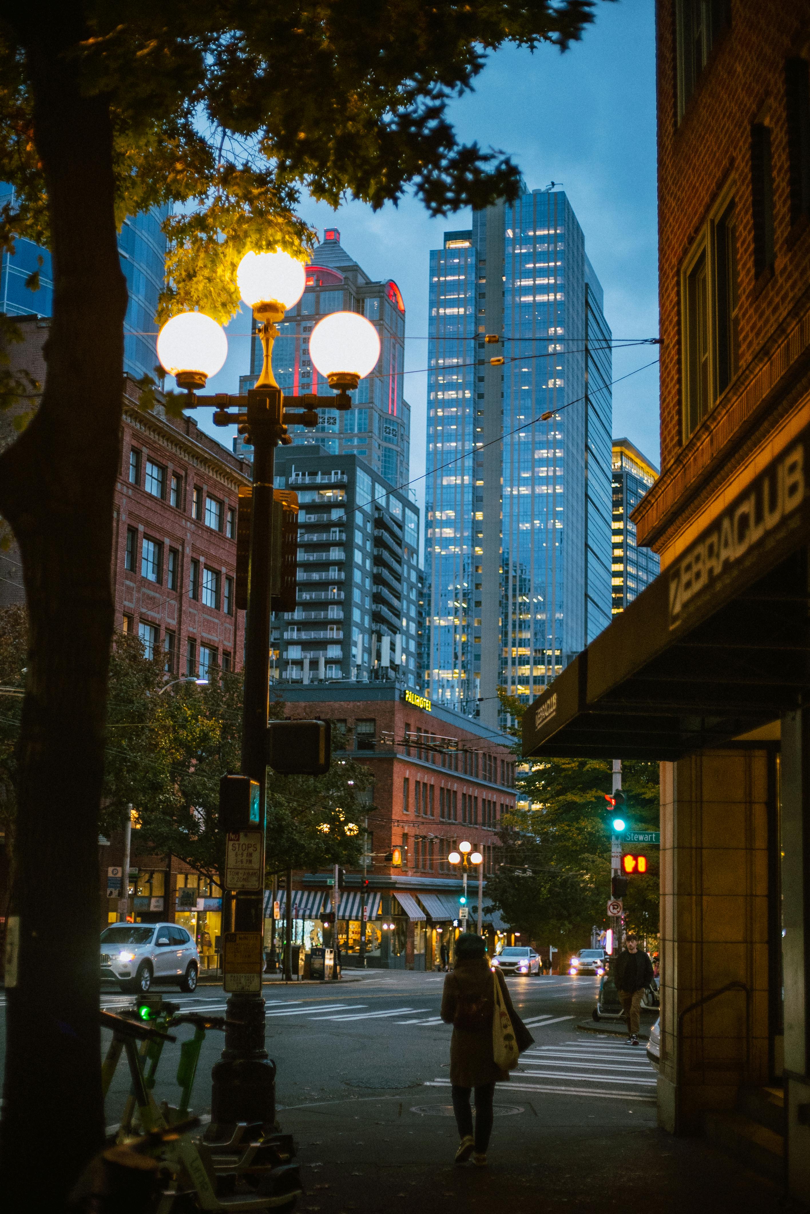 people walking on sidewalk near high rise buildings during night time