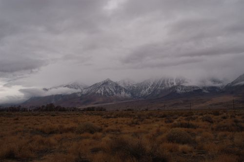 Free Snow-covered mountains with dense clouds in an open grassland during winter. Stock Photo