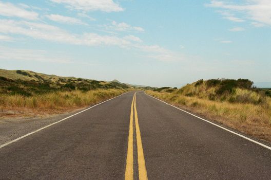 Long open road stretching through the scenic countryside beneath a clear sky.
