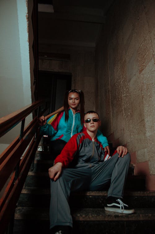 Young Boy and Girl Sitting on a Staircase in a Building 