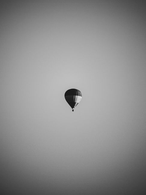 A lone hot air balloon floating against a grayscale sky, creating a serene scene.