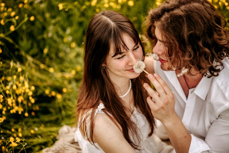 Woman Sniffing Dandelion Sitting In Mans Arms