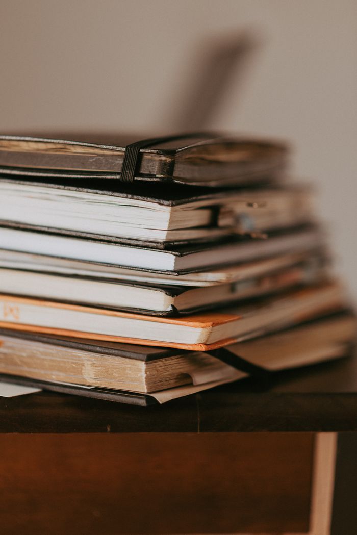 A stack of worn cloth notebooks bound with an elastic strap, photo by Jessika Arraes on Pexels