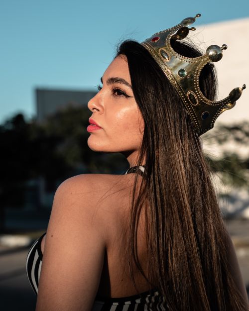 Free Close-up portrait of a woman in a crown, showcasing regal beauty in natural light. Stock Photo