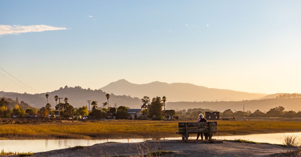 person sitting quietly on a bench overlooking the Volta River at sunset