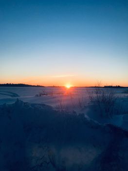 A beautiful sunrise over a snow-covered field, capturing the serene winter atmosphere.
