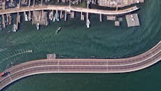 从空中俯瞰雅加达海滨，蜿蜒的高速公路和码头旁停泊着渔船