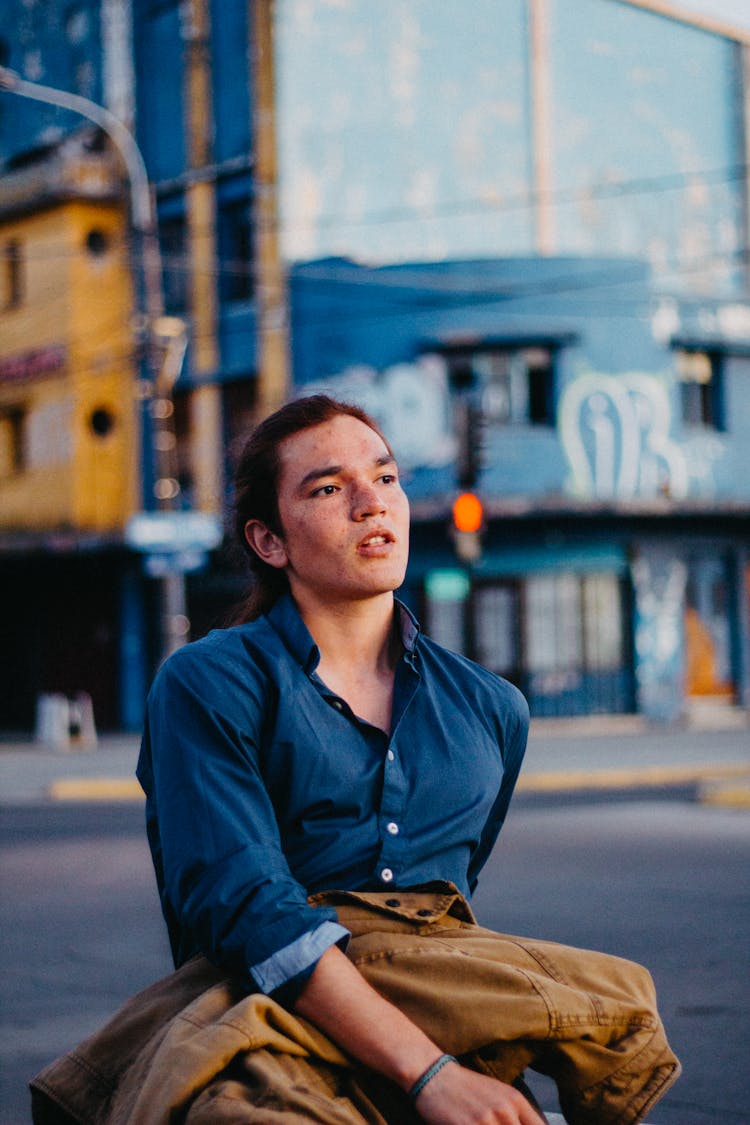 Man In Jean Shirt Sitting On Street Corner