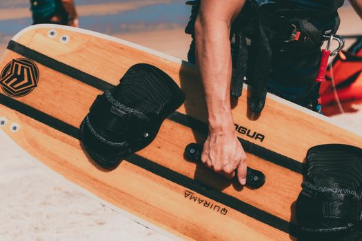 Wooden wakeboard with black straps and handle, ideal for water sports enthusiasts.