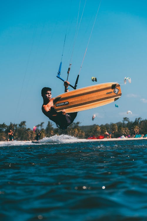 Photograph of a Topless Man Doing a Kiteboard Trick