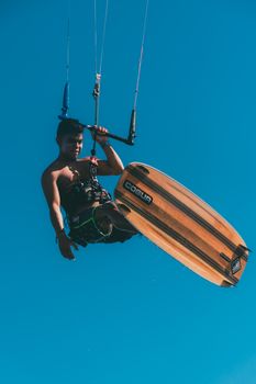 Exciting capture of a kiteboarder performing in midair against a clear blue sky.