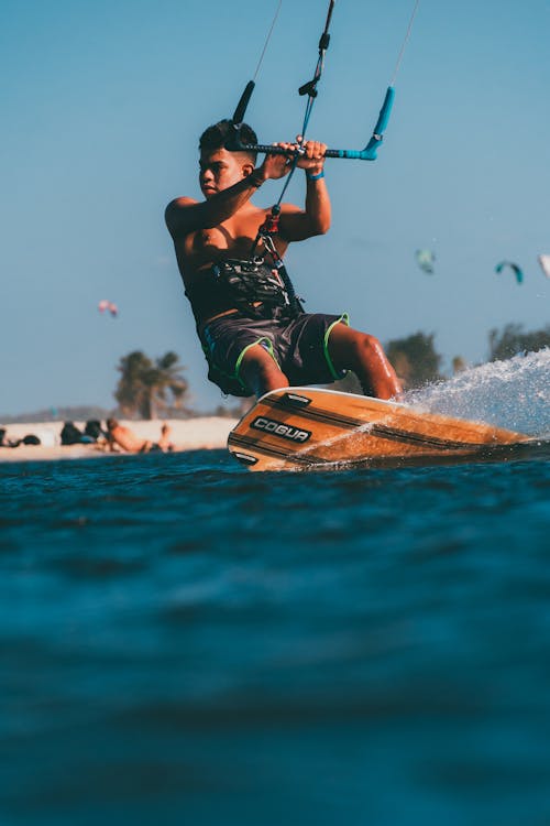 Photograph of a Man in Black and Green Shorts Kiteboarding