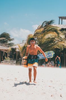 Smiling young man with wakeboard on a sunny beach, capturing summer leisure vibes.
