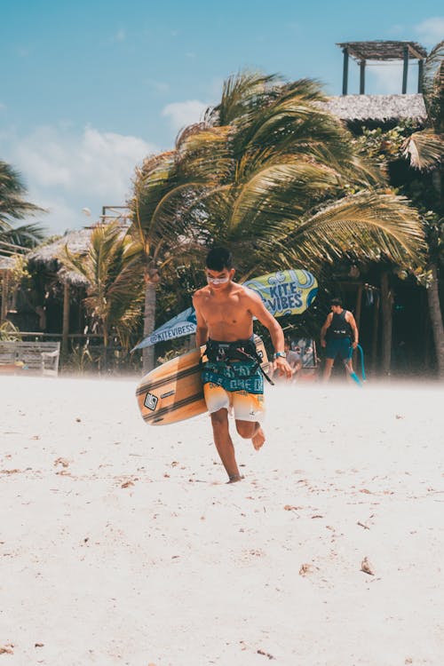 Man Holding a Wakeboard Running on the Beach 