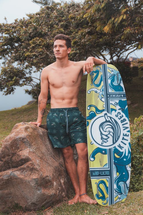 Shirtless Man Standing Beside a Surfboard