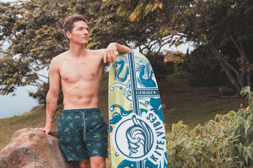 Topless Man Standing Beside Surfboard