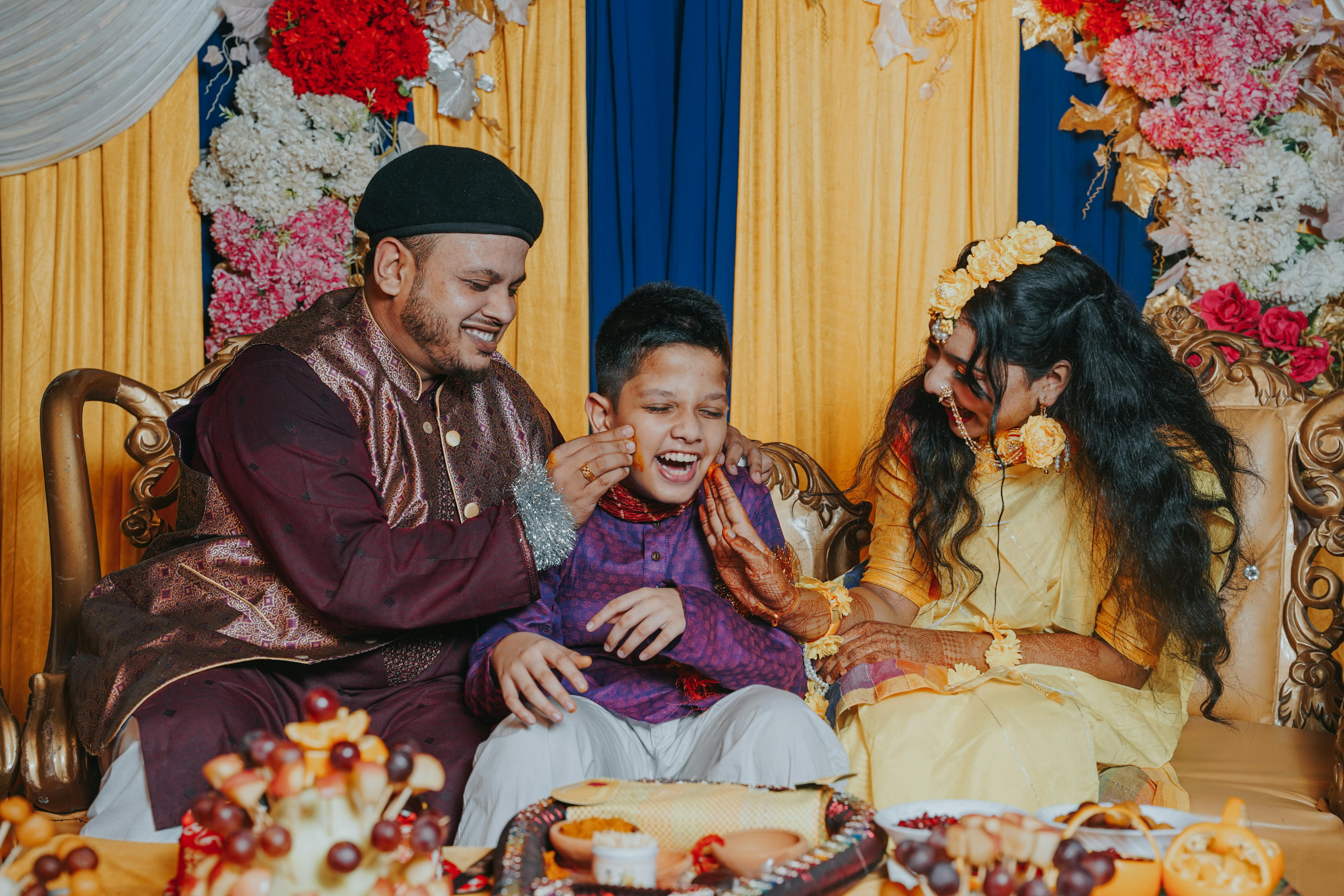 family wearing traditional clothing sitting and smiling during a ceremony